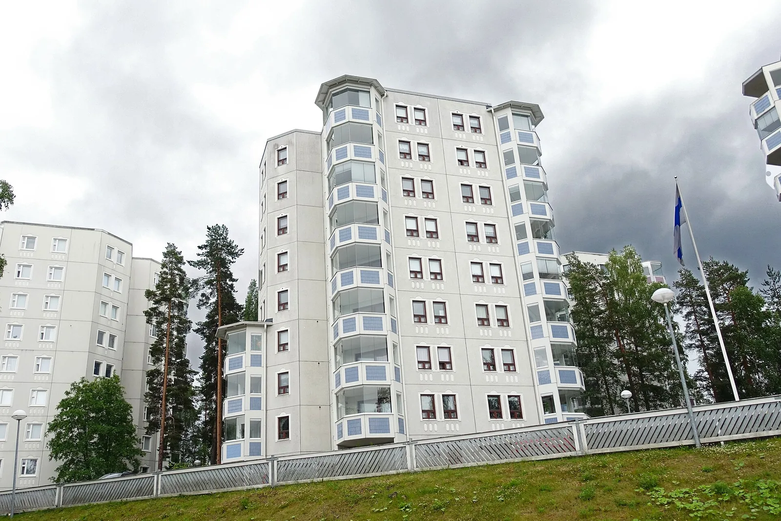 Vaalea kerrostalo mäen rinteellä asuinalueella