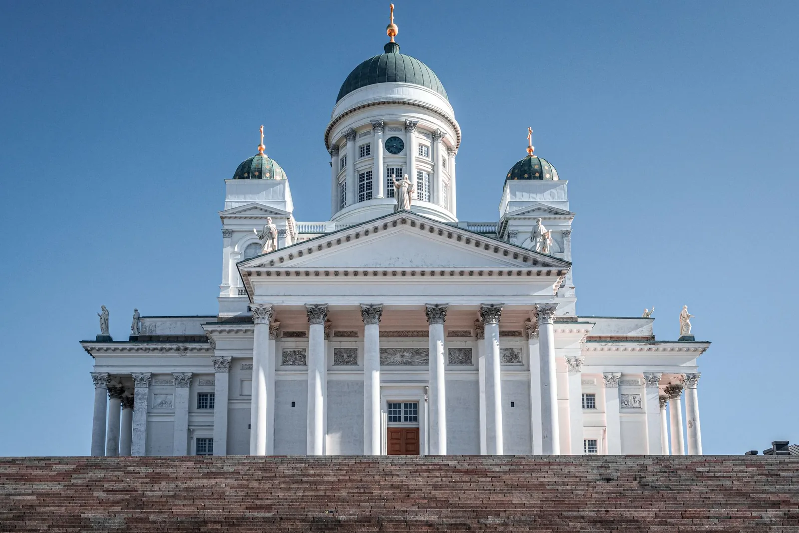 Vaalea uusklassinen kirkko edestä katsottuna kirkkaalla taivaalla