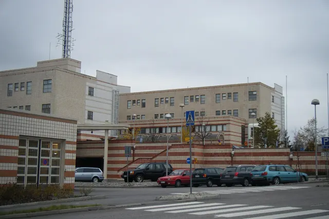 Sairaalan vaaleat rakennukset ja pysäköintialue kadun varrella