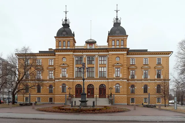 Keltainen kaupungintalo kahden tornin kanssa pilvisenä päivänä