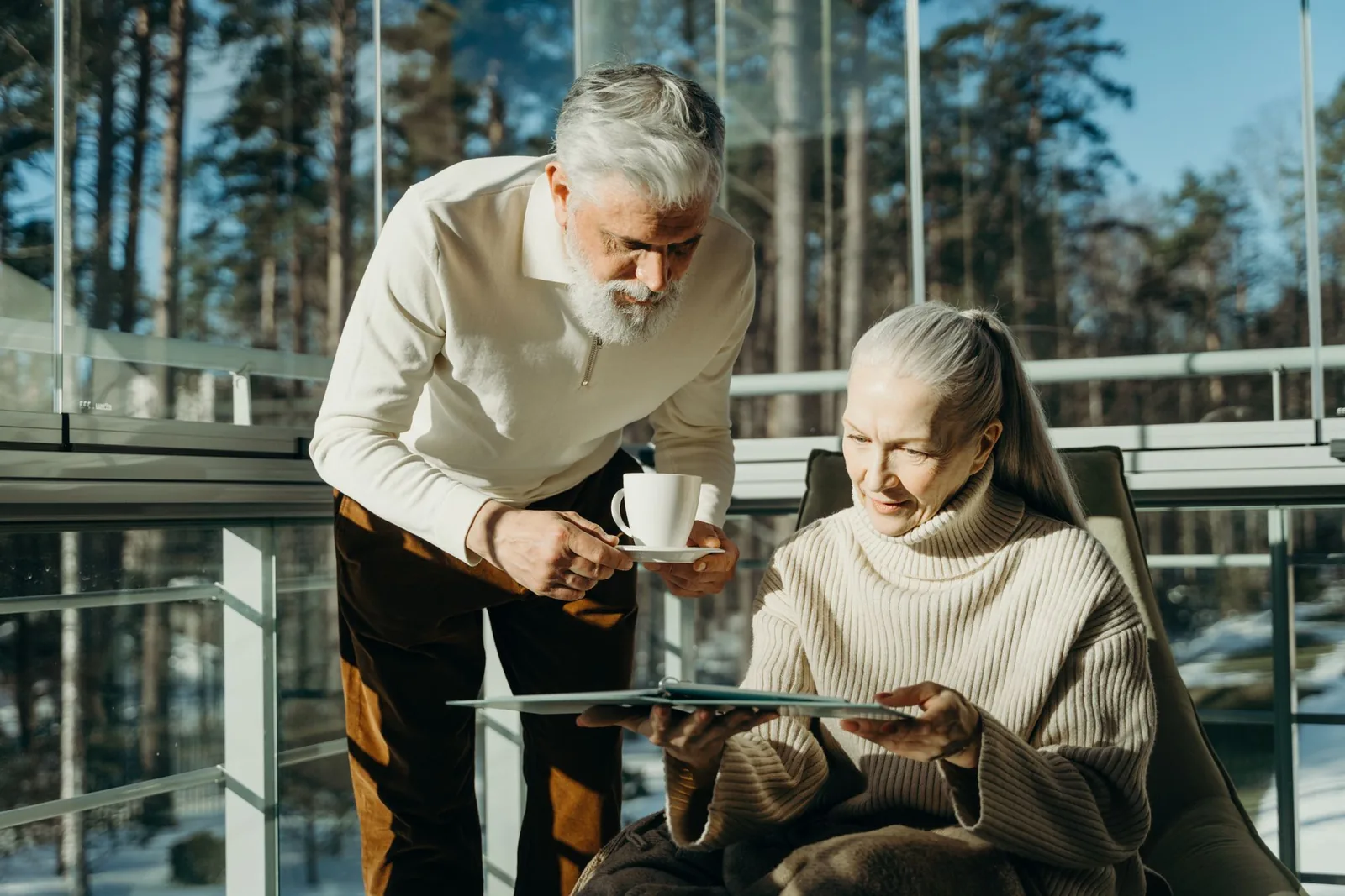 Ikääntynyt pariskunta lukee kahvin ääressä valoisassa huoneessa