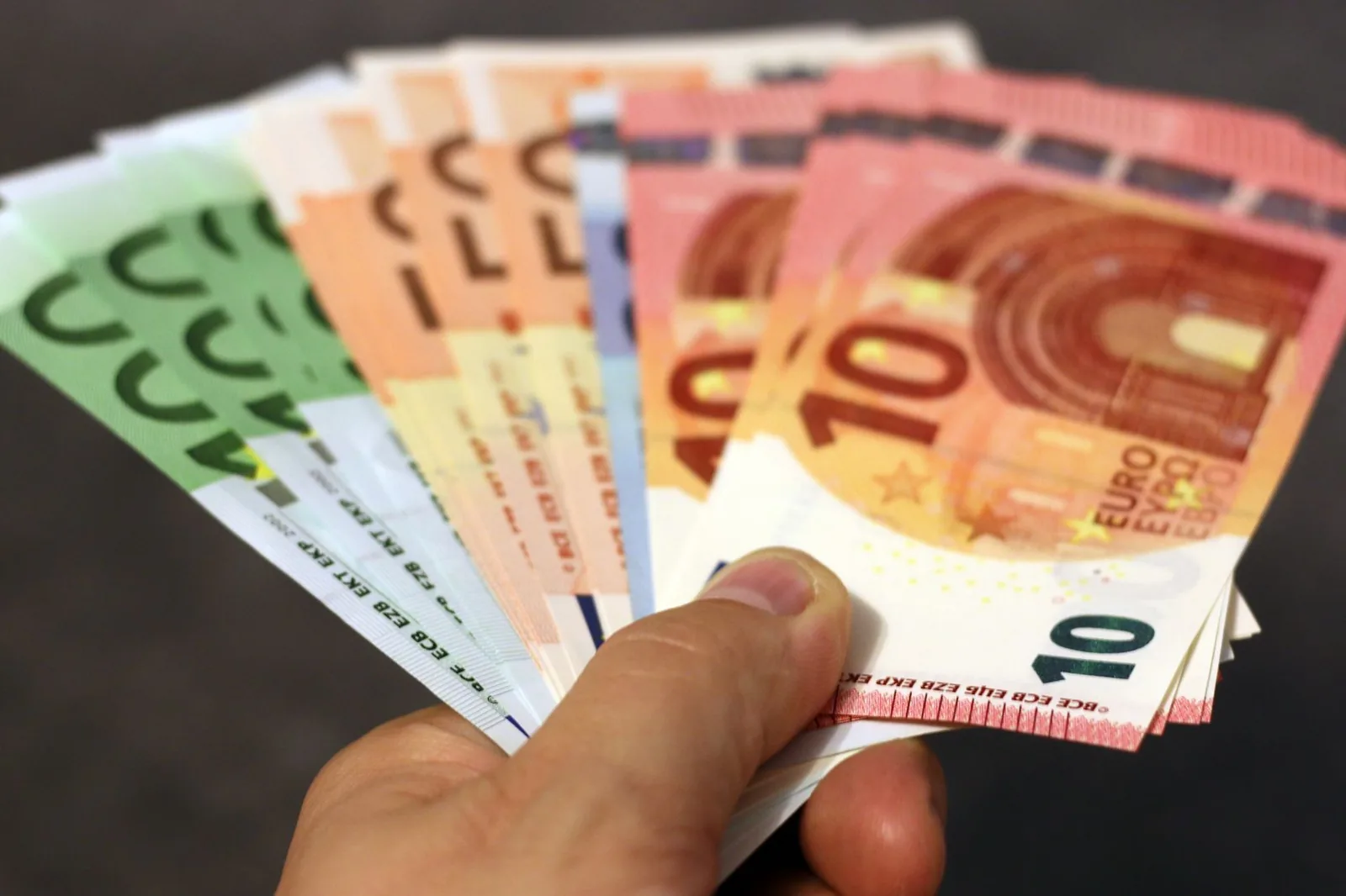 Käsi pitelee viuhkana useita euroseteleitä