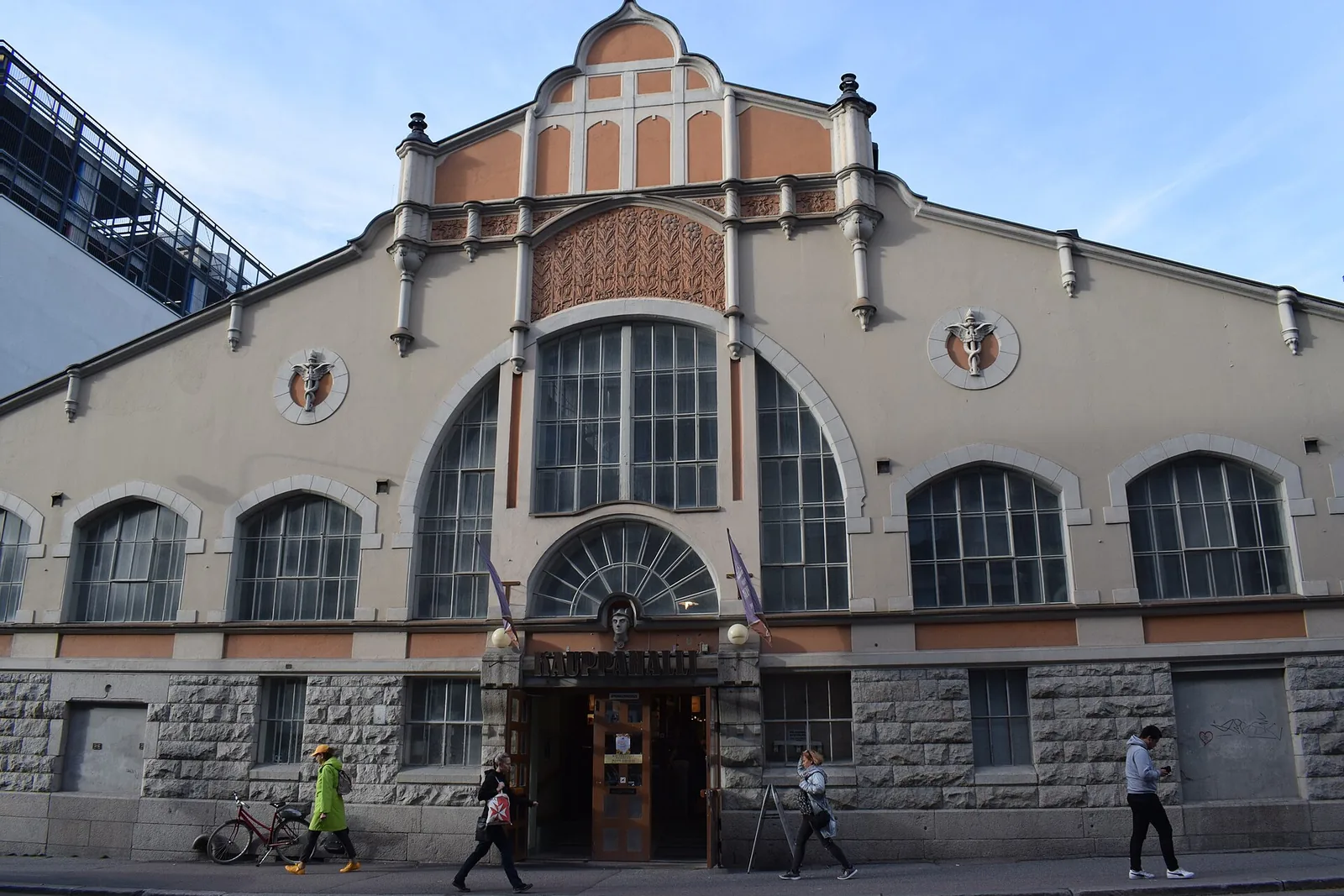 Vanha kivi- ja rappauspintainen kauppahallirakennus ja ohikulkijoita kadulla